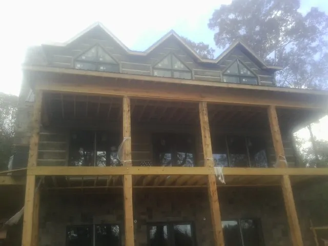 Dormers and porch framing on a large log home under construction — Roof Coating work by our crew in Maysville